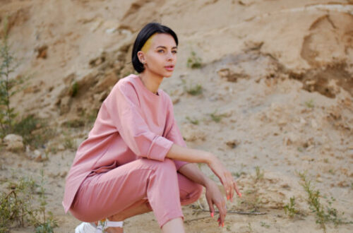 Stylish woman in modern sandals squatting in mountains